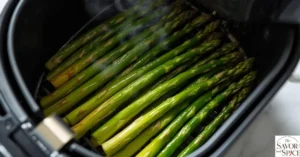 Fresh asparagus cooking in an air fryer basket, golden-tipped and crisp.
