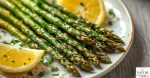 Plated air fryer asparagus garnished with lemon wedges and Parmesan cheese, ready to serve.