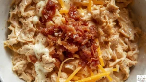 Mixing shredded chicken, crispy bacon, ranch dressing, and shredded cheeses in a bowl to make creamy calzone filling.