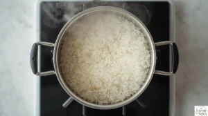 Simmering white rice in a covered saucepan over low heat until the water is absorbed and the rice is tender.
