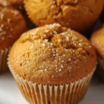 Close-up of tall, soft, bakery-style pumpkin spice muffins fresh out of the oven, golden brown tops, perfectly spiced, cozy fall treat.